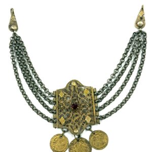 Traditional filigree chest ornament with red decorative stone and hanging coins.